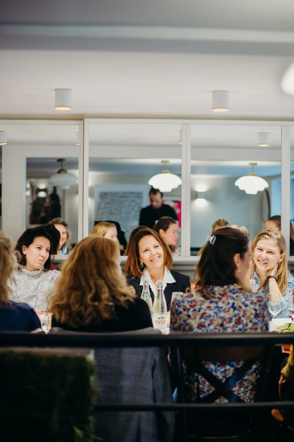Groupe de femmes assises à une table lors d'un repas dans un restaurant, discutant et souriant.