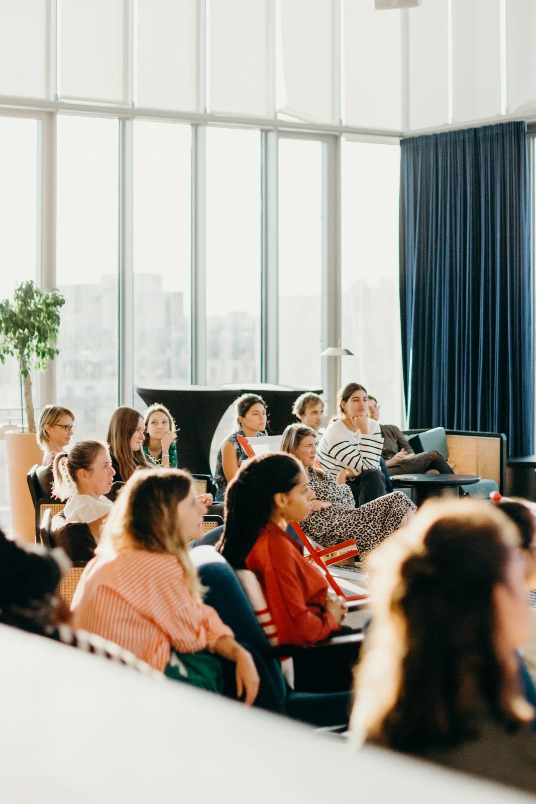 Groupe de personnes assises dans une salle lumineuse lors d'une conférence ou d'un atelier.