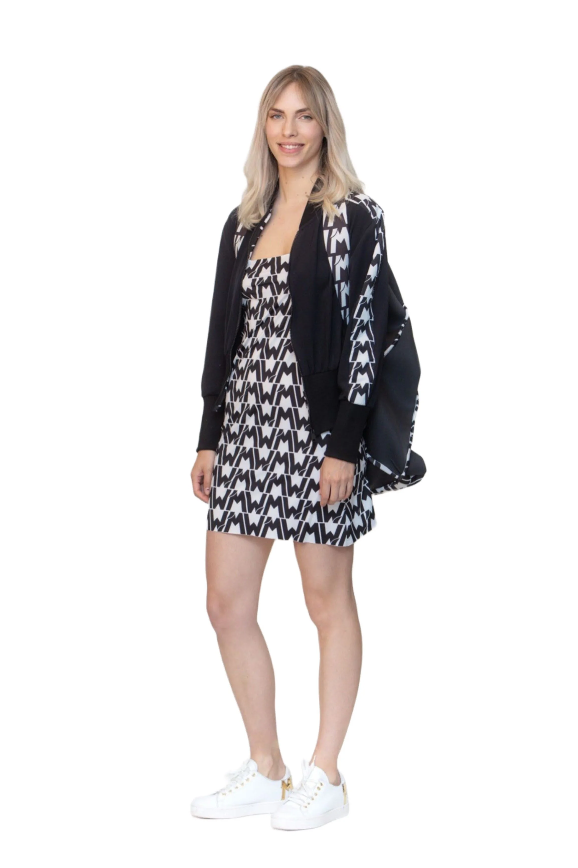 Una donna con abbigliamento nero e bianco, vestita con un vestito e una felpa con cappuccio, e scarpe biane si trova su uno sfondo bianco.