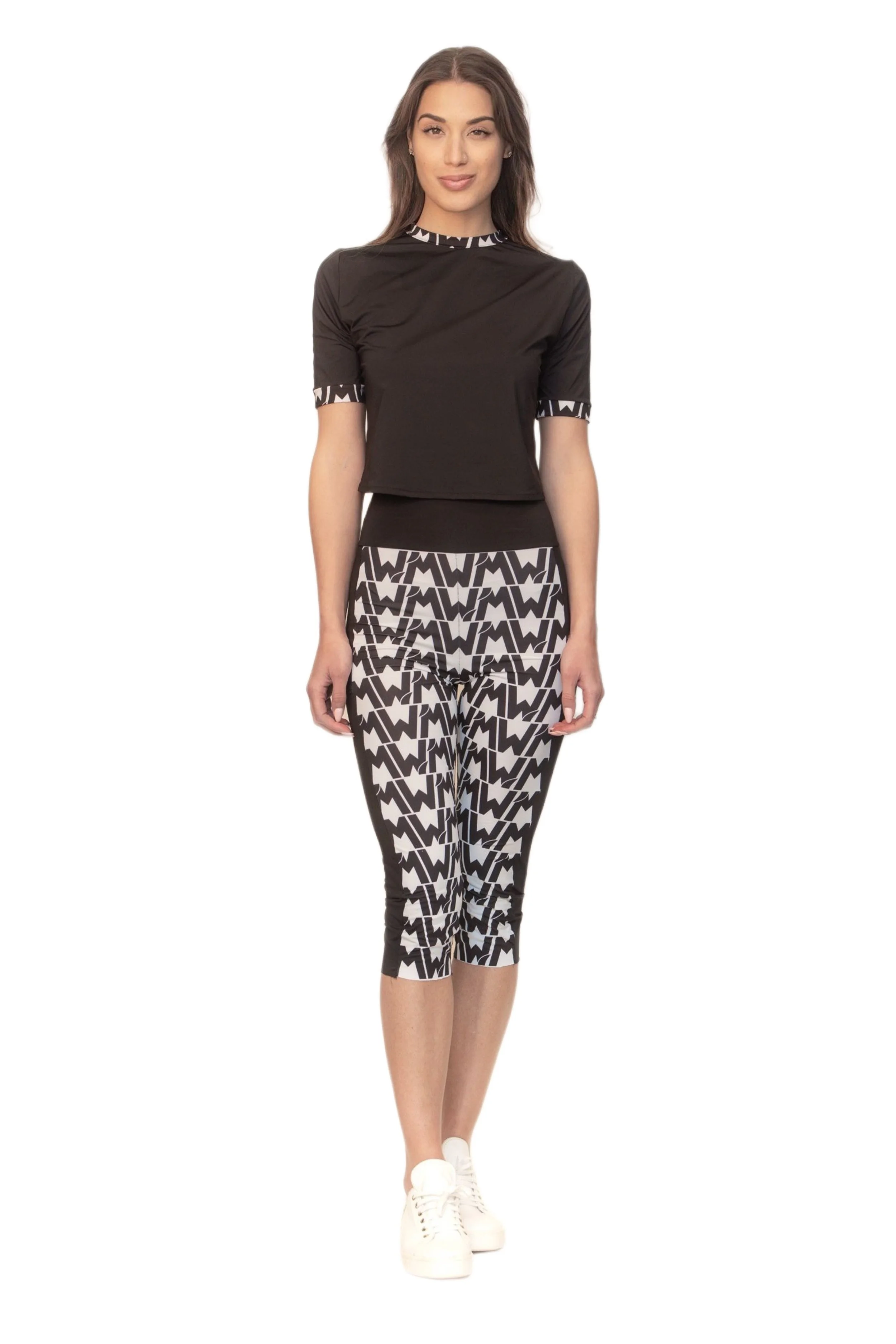 Donna che indossa un abbigliamento sportivo con pantaloni e top nero con motivi geometrici bianchi