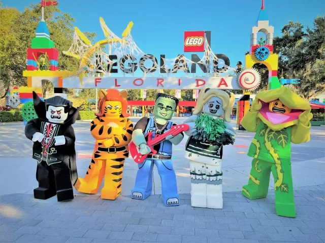 Lego figures of iconic characters from The Addams Family and Lil' Debbie at Legoland Florida with the entrance sign in the background.