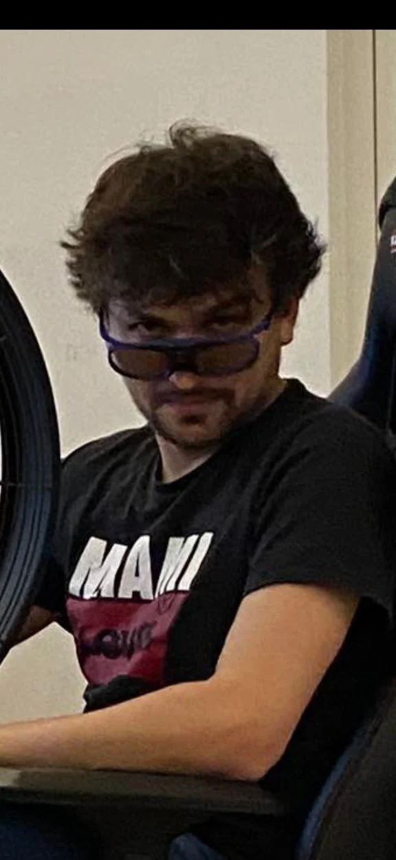 Jeune homme avec lunettes assis devant un ordinateur, portant un t-shirt noir