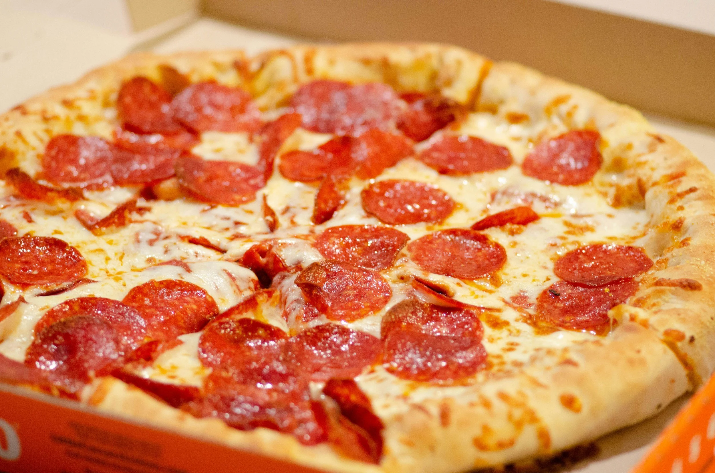 Pepperoni pizza in a cardboard box with a golden crust, melted cheese, and pepperoni slices.