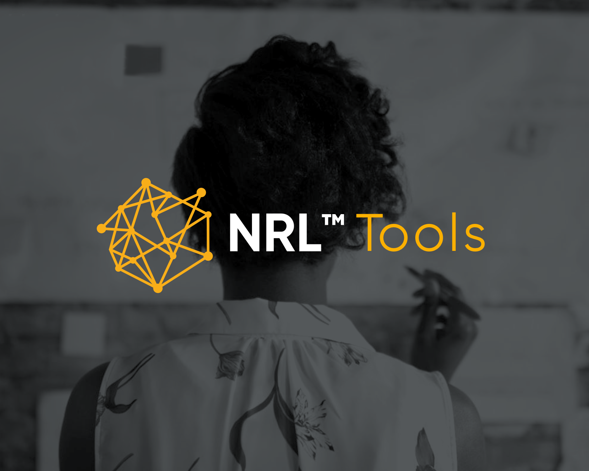 A person with short curly hair writing on a whiteboard in a classroom, with the overlay text 'NRL™ Tools' and a geometric network icon.