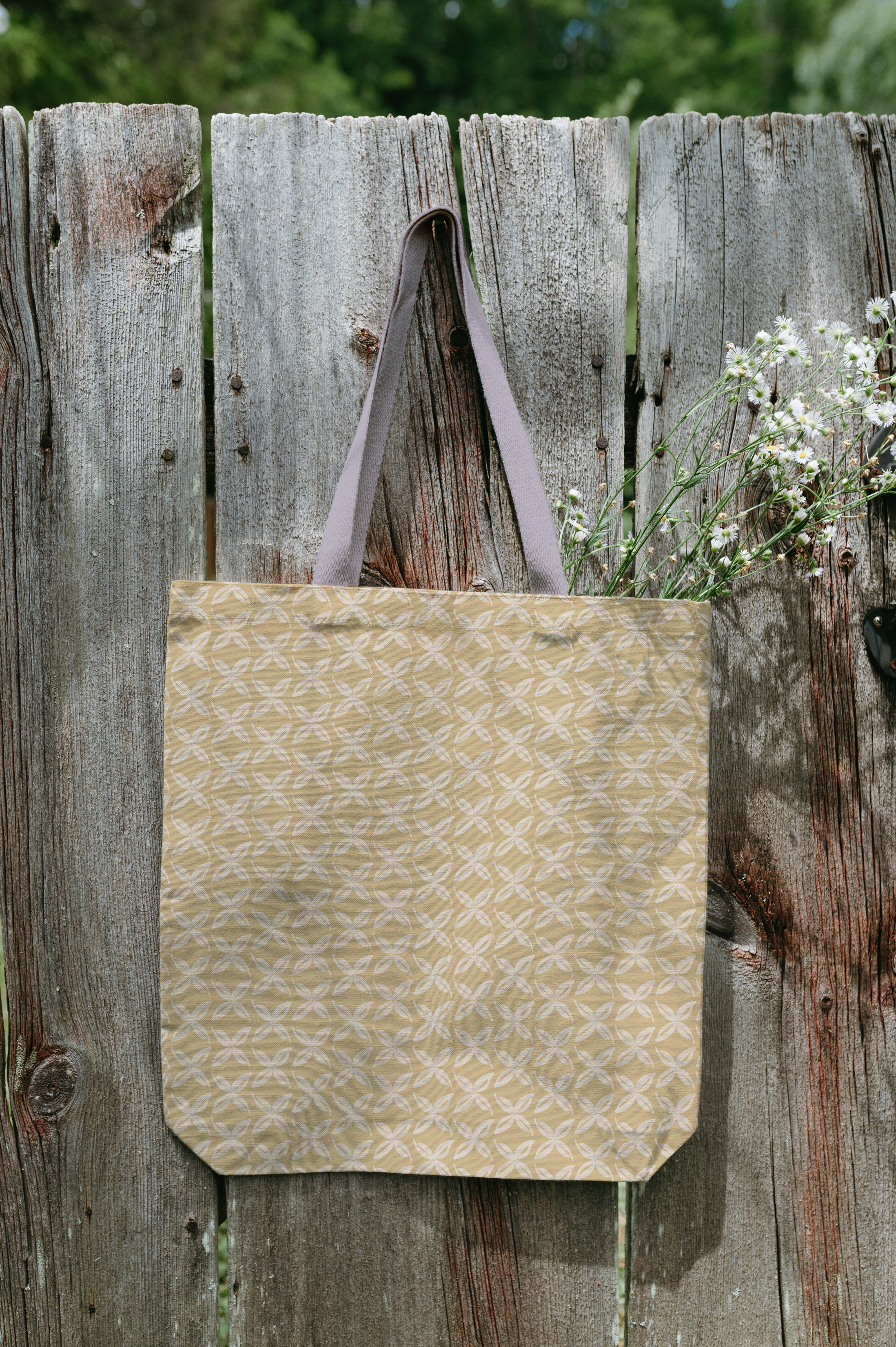 Tote bag hanging on a fence with a yellow floral pattern.