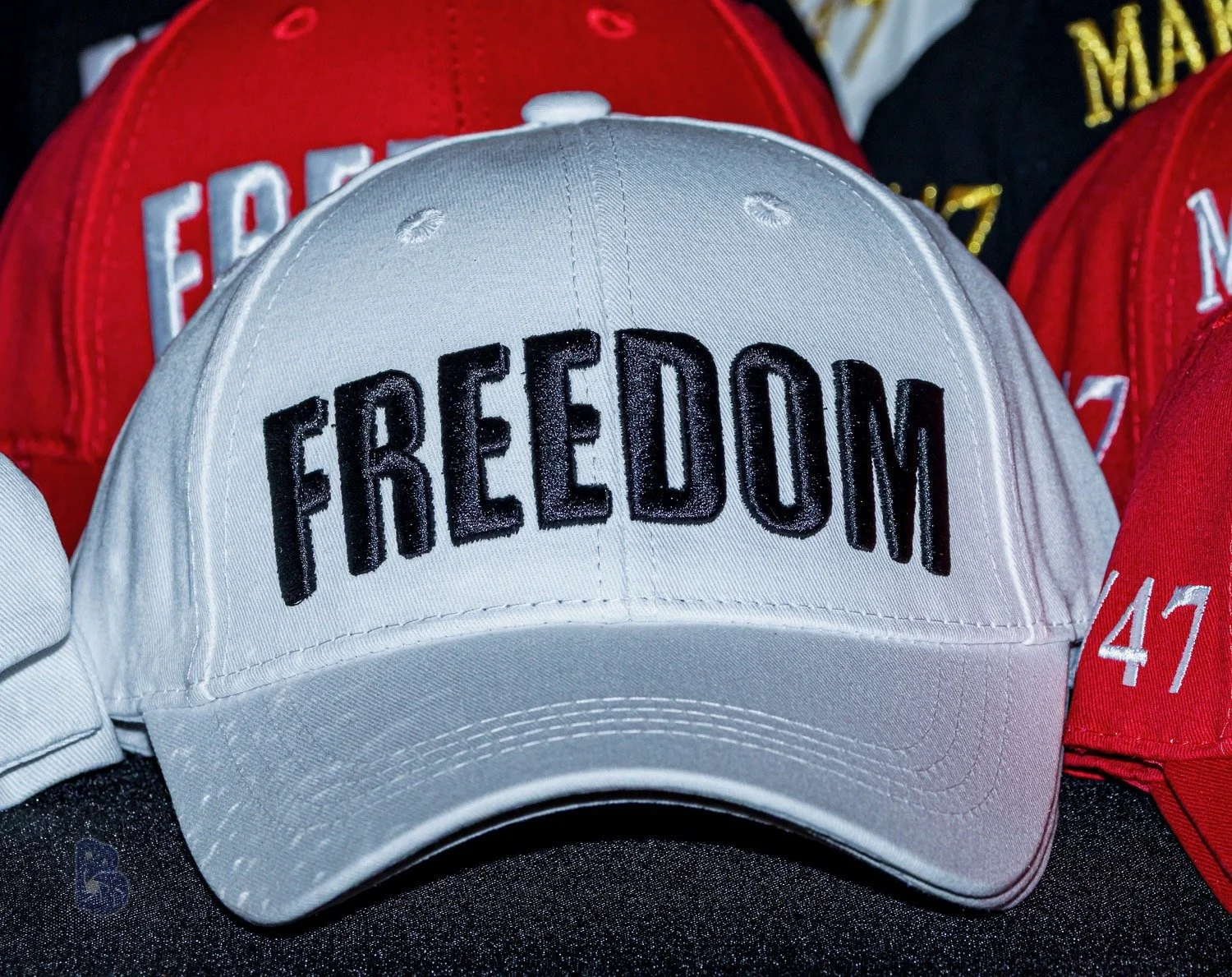 A white baseball cap with the word 'FREEDOM' embroidered in black on the front.