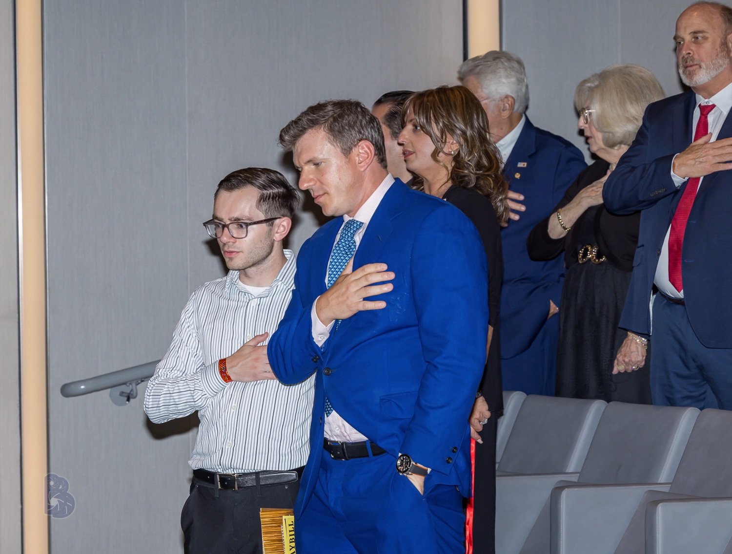 Group of people standing with their hands over their hearts during a formal event.