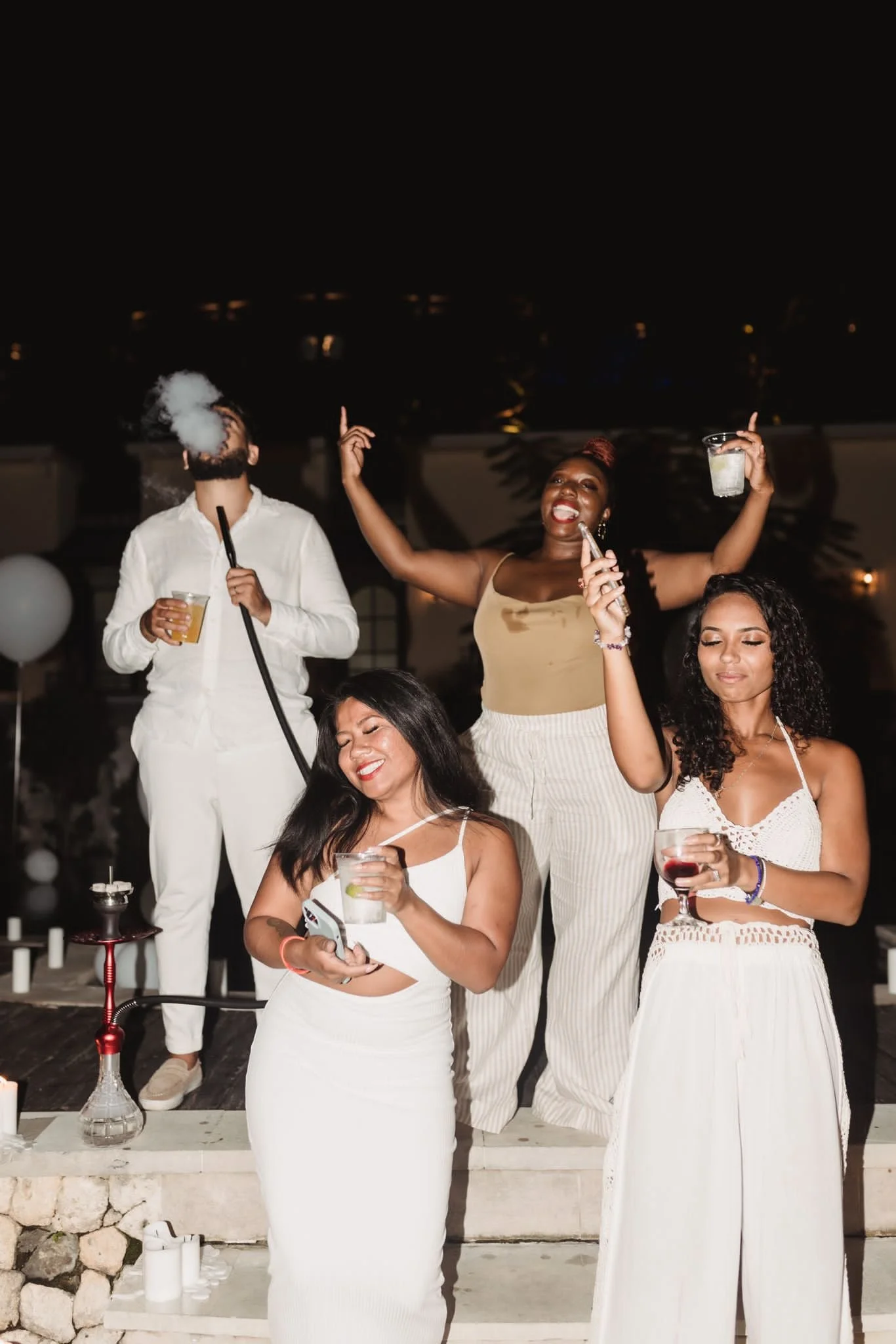 Group of people at a party, dressed in white and beige outfits.