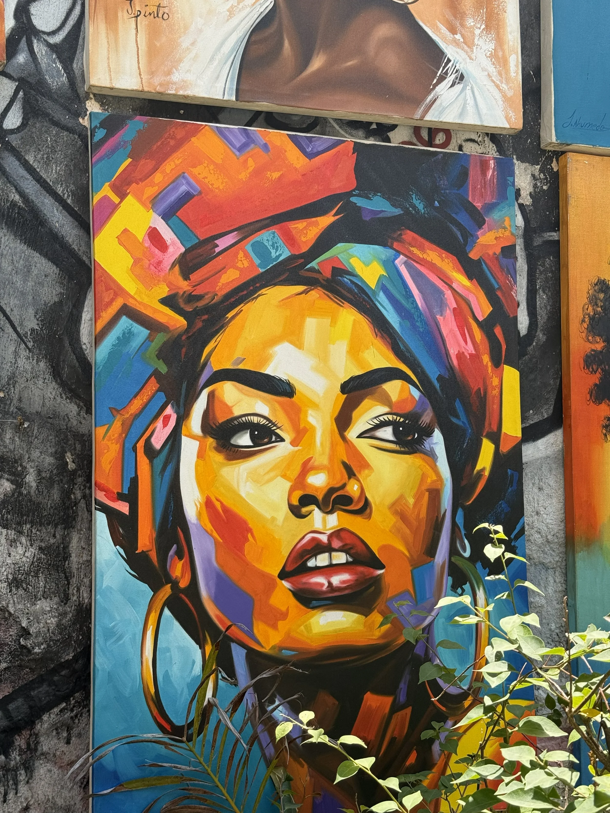 Bright, colorful painting of a woman with a headwrap, showcasing bold facial features and expressive eyes.