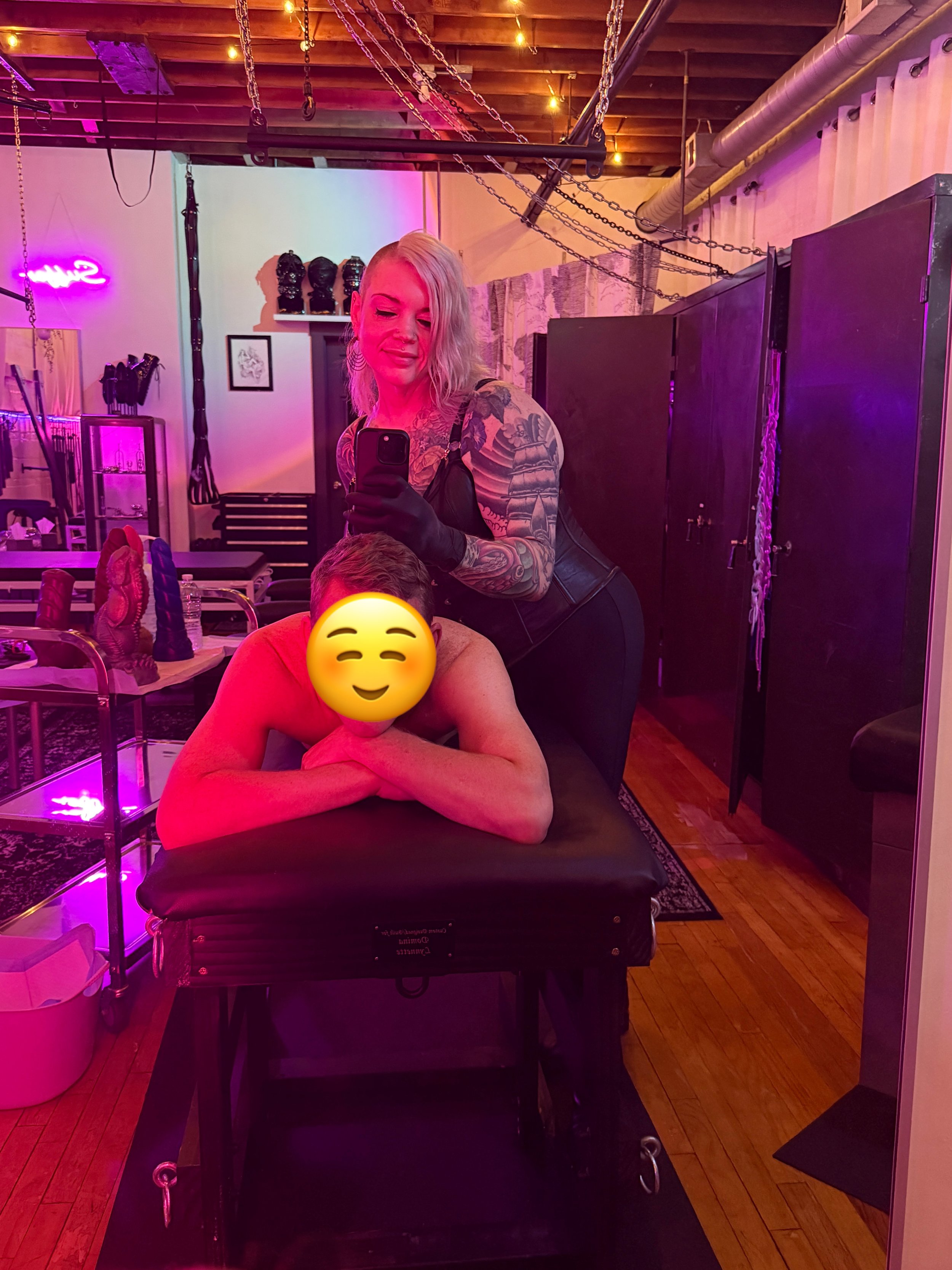 Chicago Mistress Erin Black is in her dungeon with a submissive on a spanking bench.