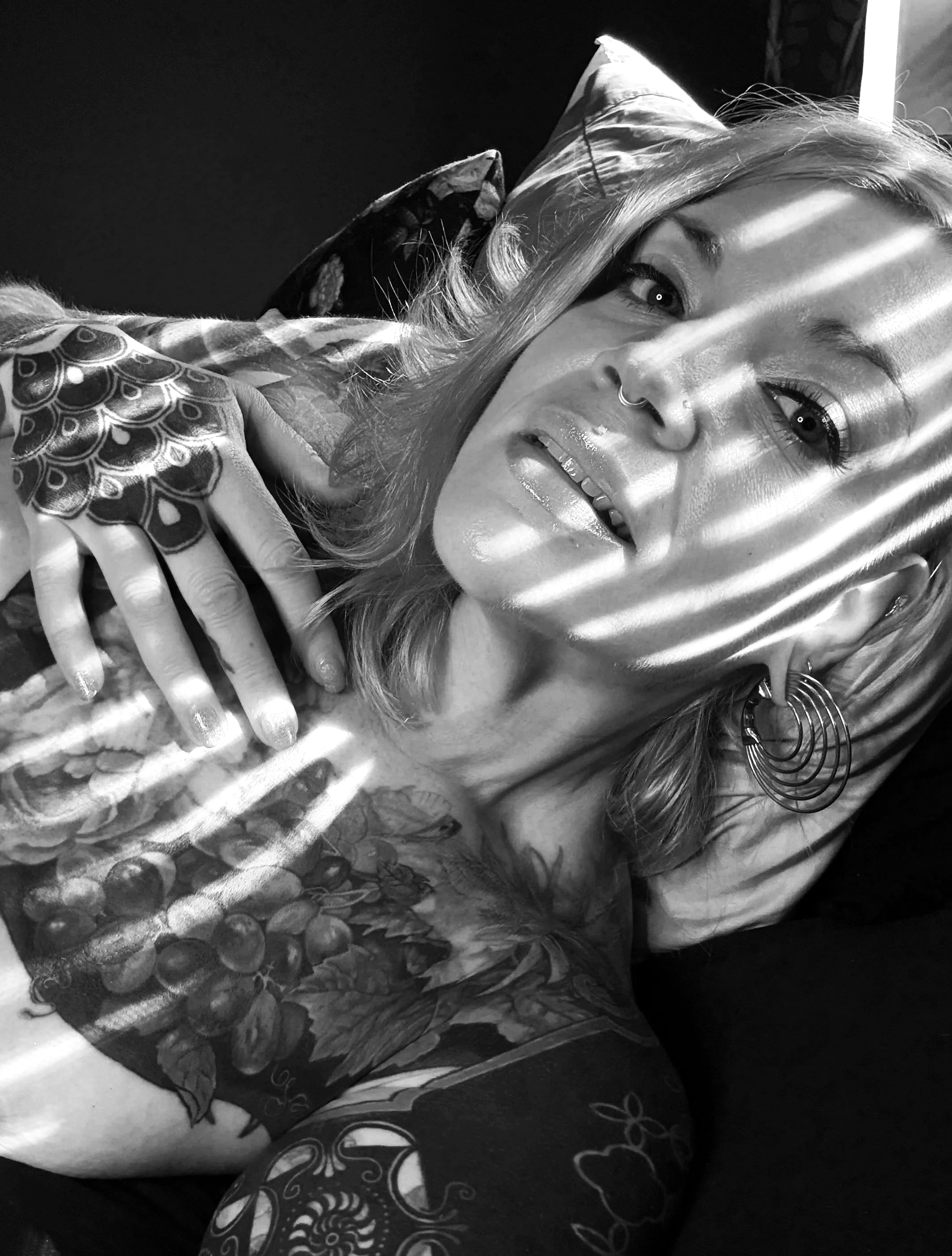 Chicago prostate massage expert Erin Black lounges with light coming through the blinds across her face and body.