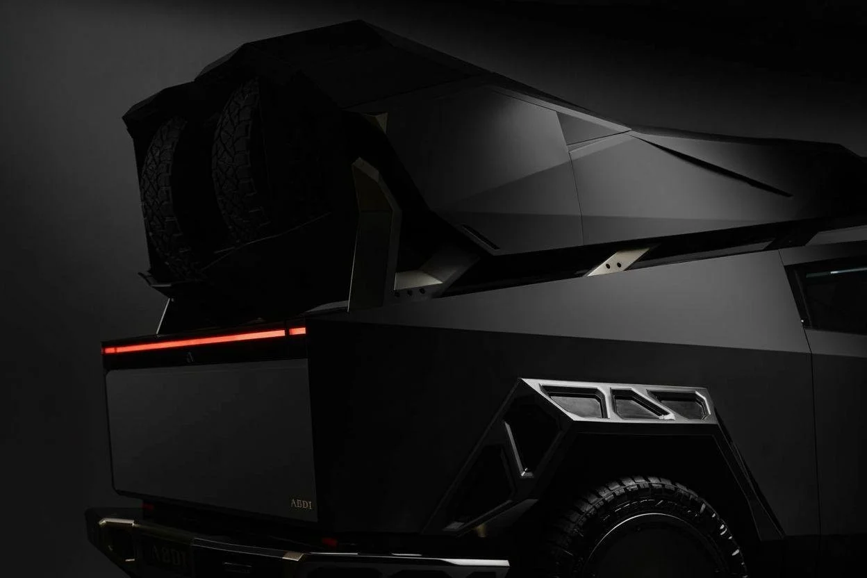 Close-up of a sleek, black futuristic vehicle with angular design and sharp lines, illuminated by subtle lighting in a dark setting.