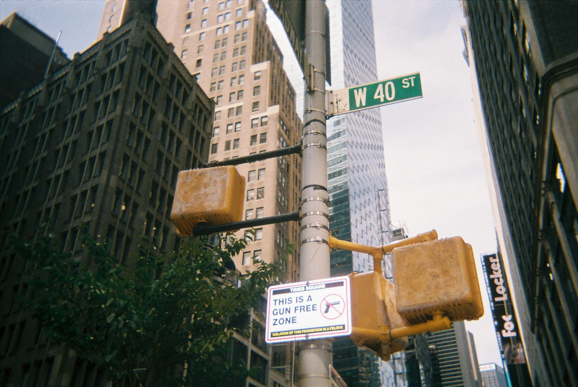 Street view at the intersection of W 40th Street in New York City, showing traffic lights, street signs, and buildings with modern and older architecture.