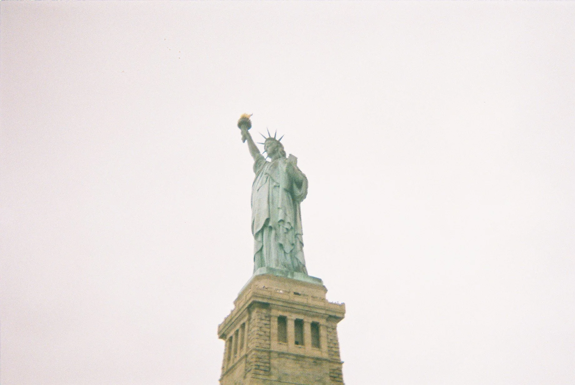 The Statue of Liberty standing tall on a cloudy sky background.