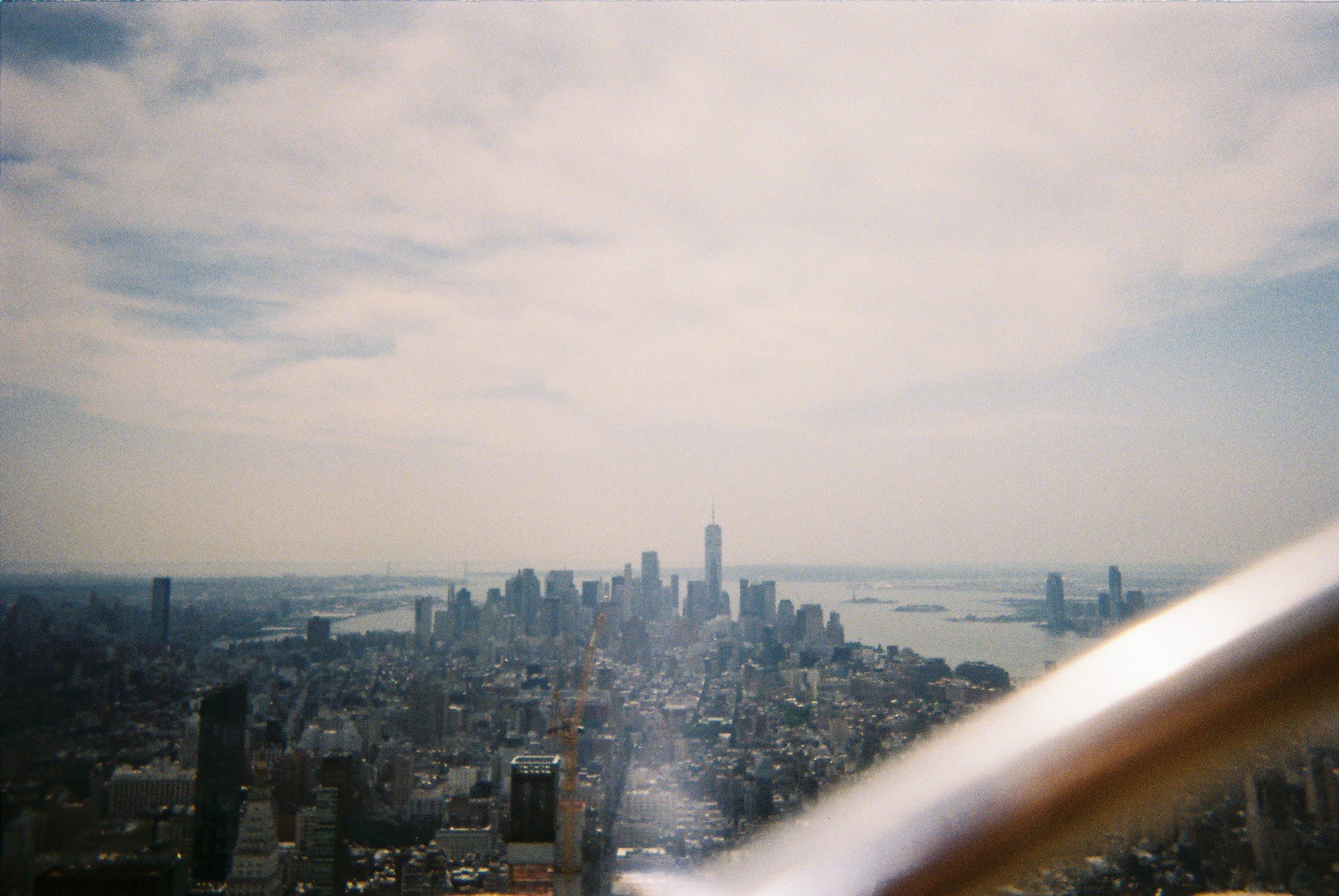 Aerial view of the New York City skyline, including the One World Trade Center, with the Hudson River in the background, taken from a high altitude.