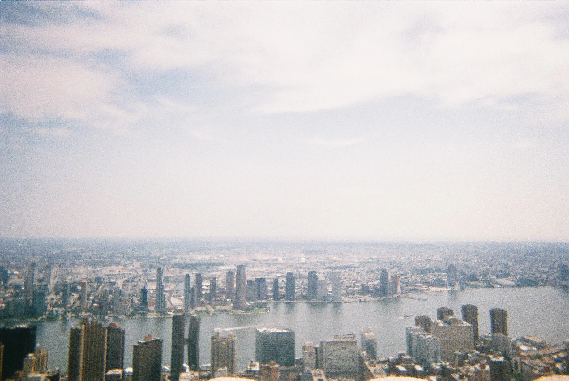 Aerial view of a city skyline with high-rise buildings and a river running through the city, under a cloudy sky.