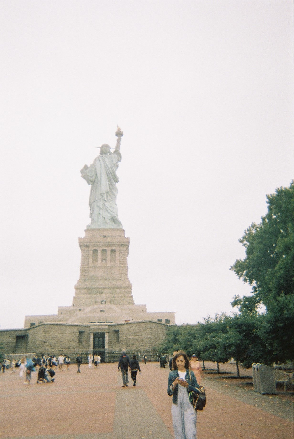 The Statue of Liberty seen from the front with tourists walking around