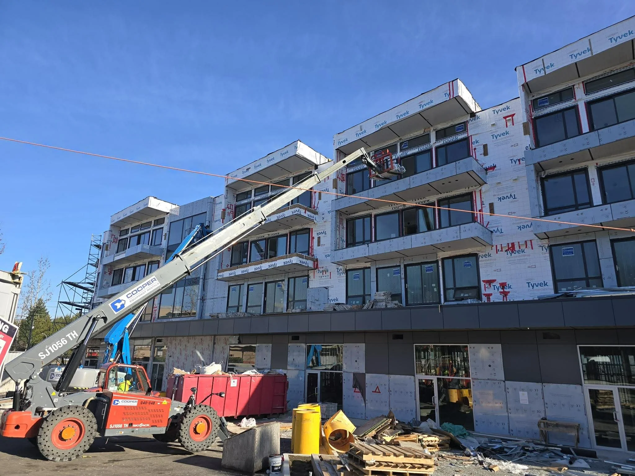 Construction site of a multi-story building with scaffolding, a crane, construction debris, and workers.