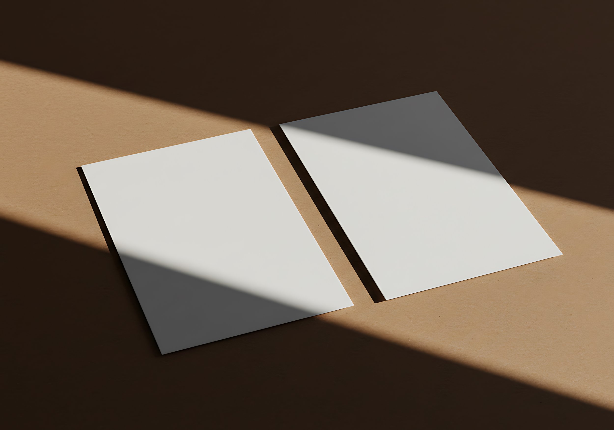 Dos hojas en blanco en una superficie de color marrón, con sombras que cruzan la imagen.