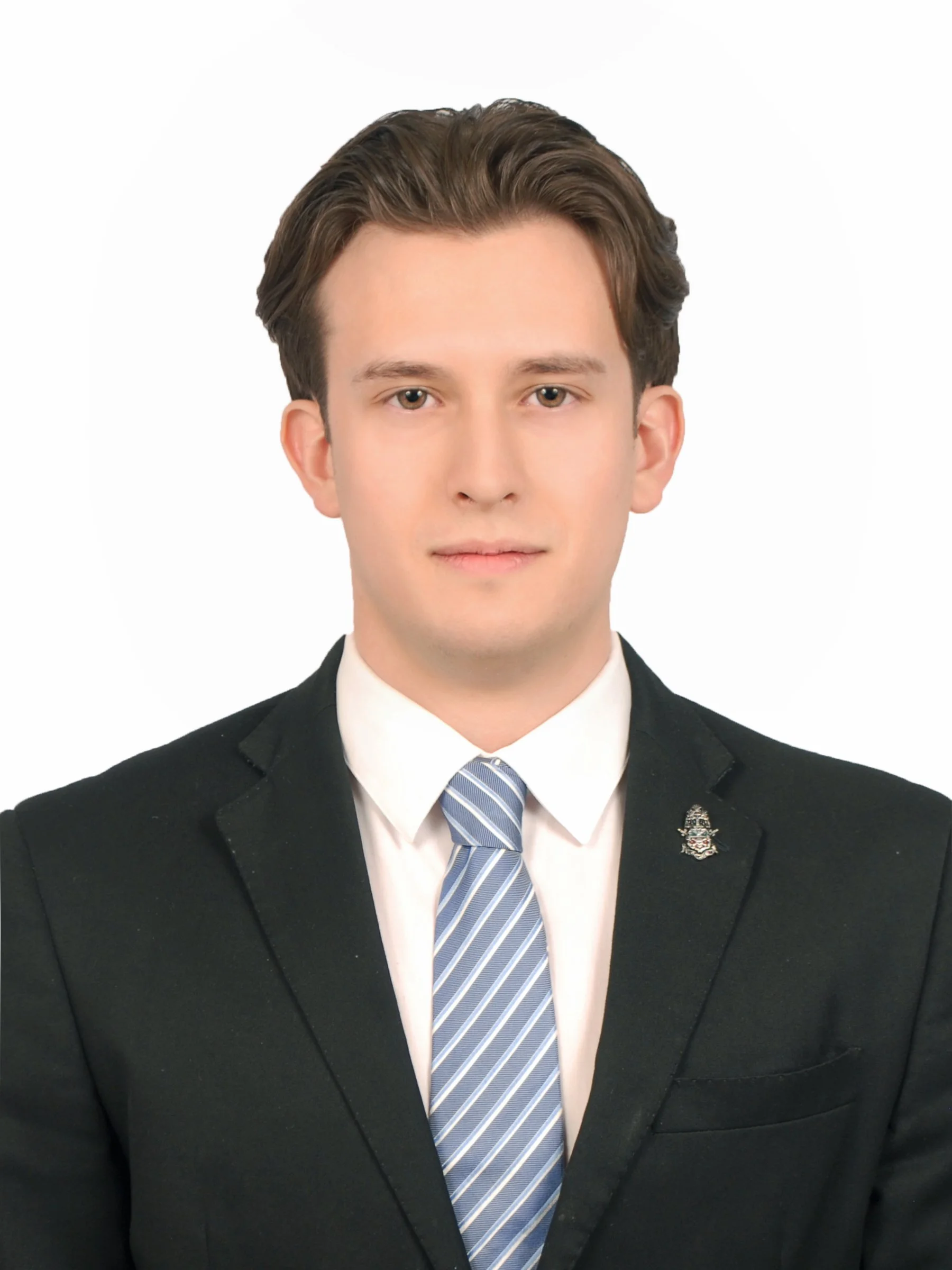 Retrato de un hombre joven con cabello castaño, vestido con saco negro, camisa blanca y corbata azul claro con rayas.