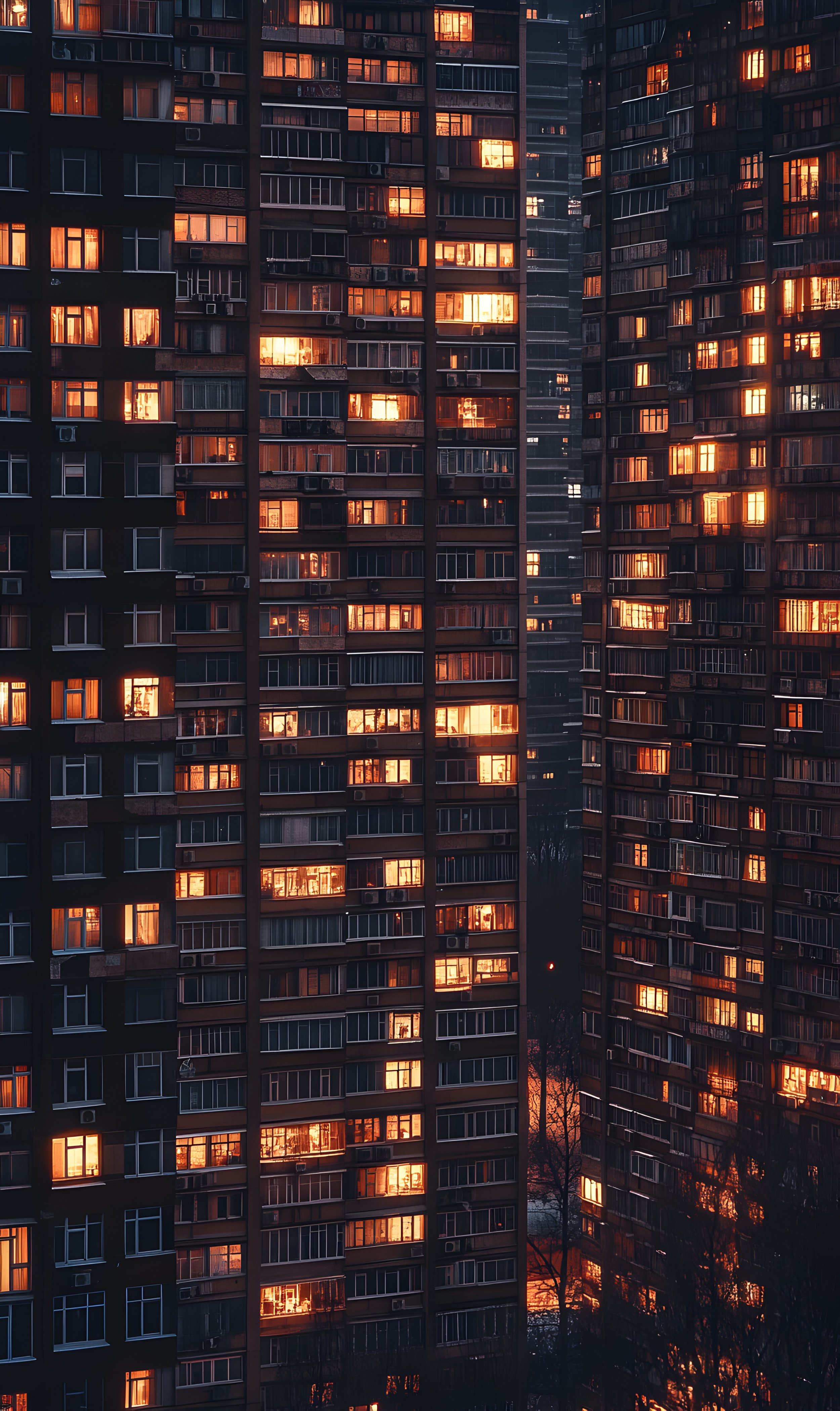 Edificios de apartamentos en la ciudad al atardecer, con ventanas iluminadas que reflejan la luz del sol poniente.