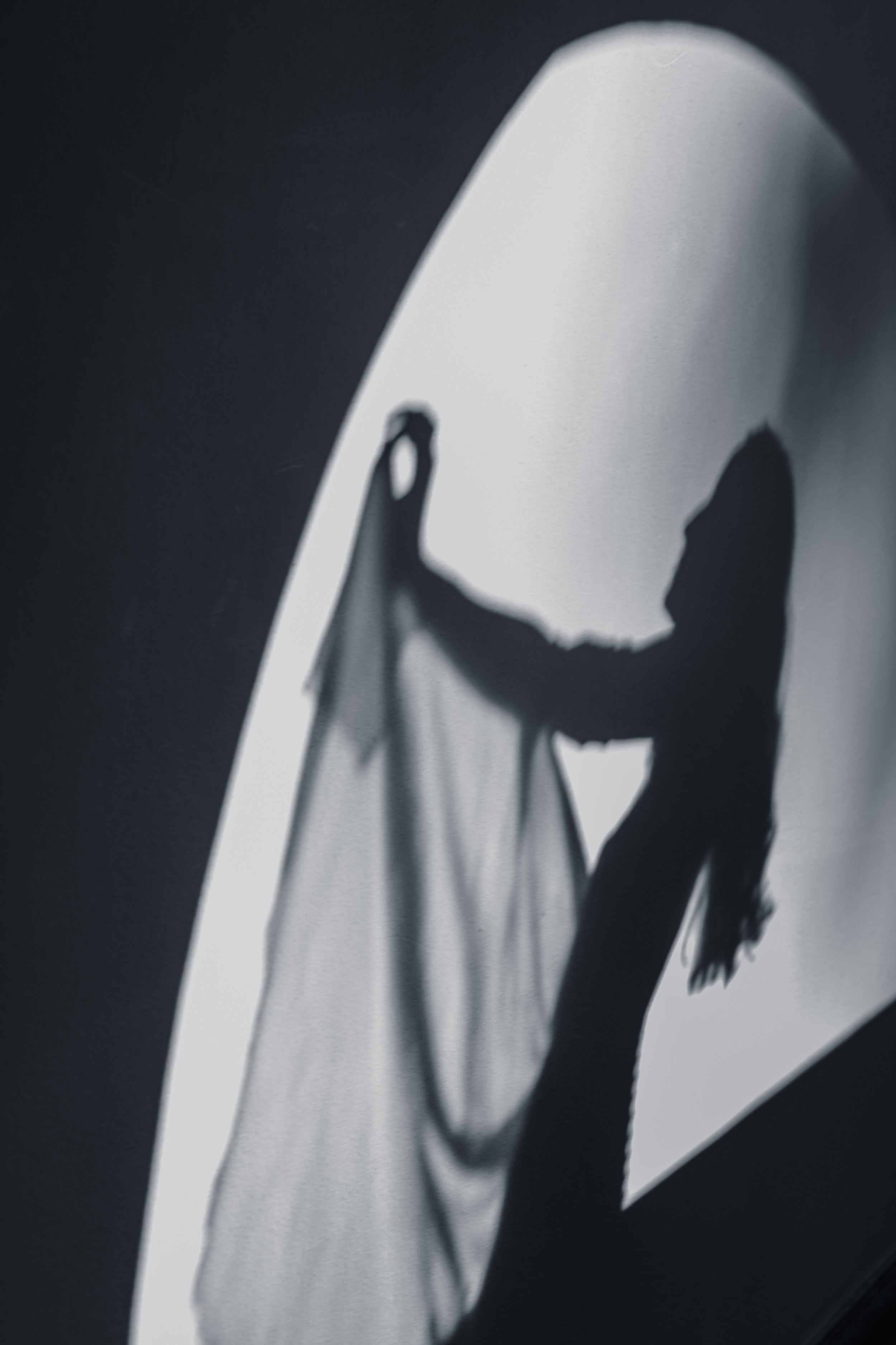 Silhouette of a woman placing a sheer fabric or curtain on a lightbox, creating a shadowy effect.