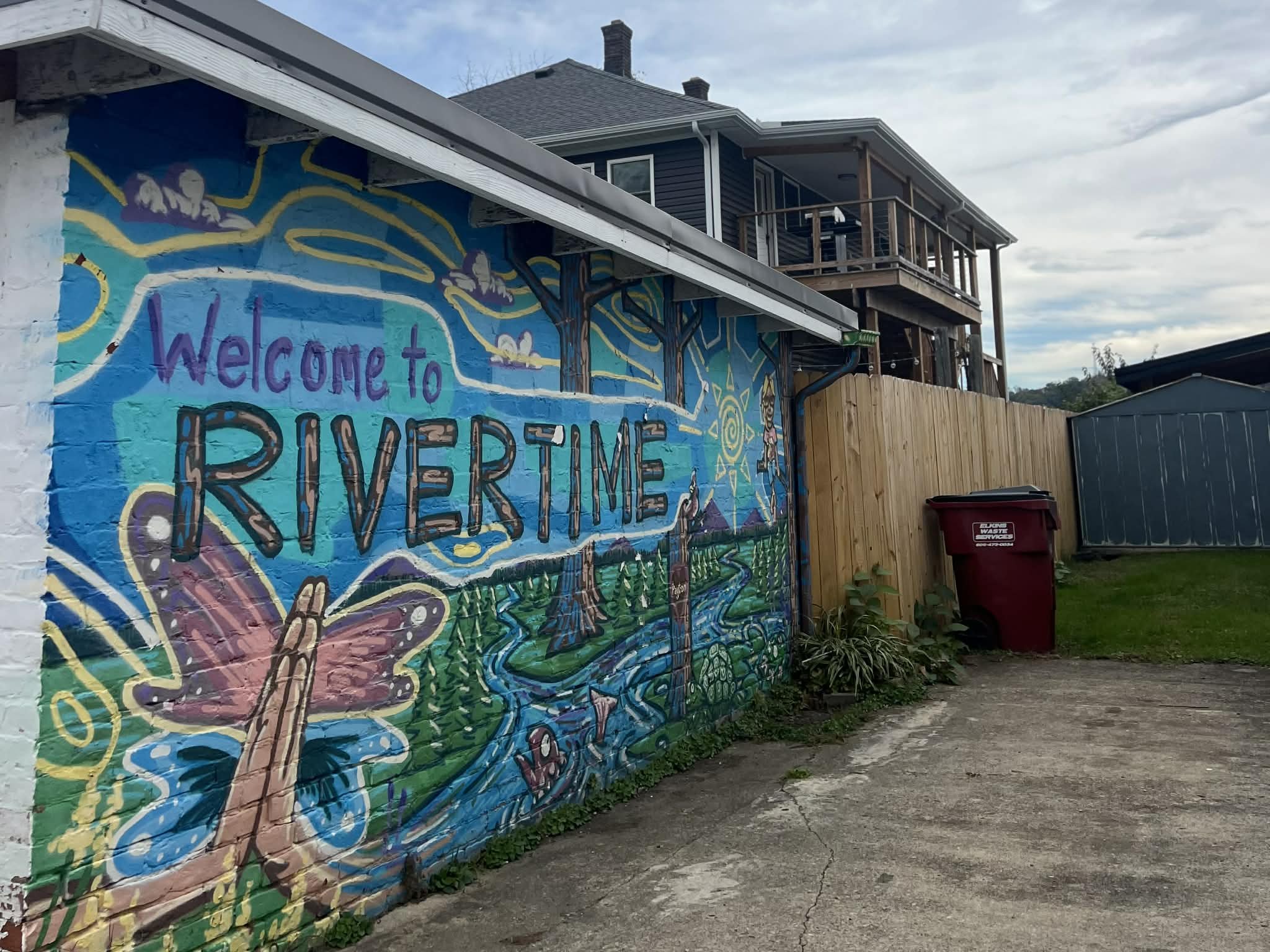 Colorful mural on a wall welcoming visitors to Rivertime, featuring a butterfly, trees, a river, mountains, and a bright sky.