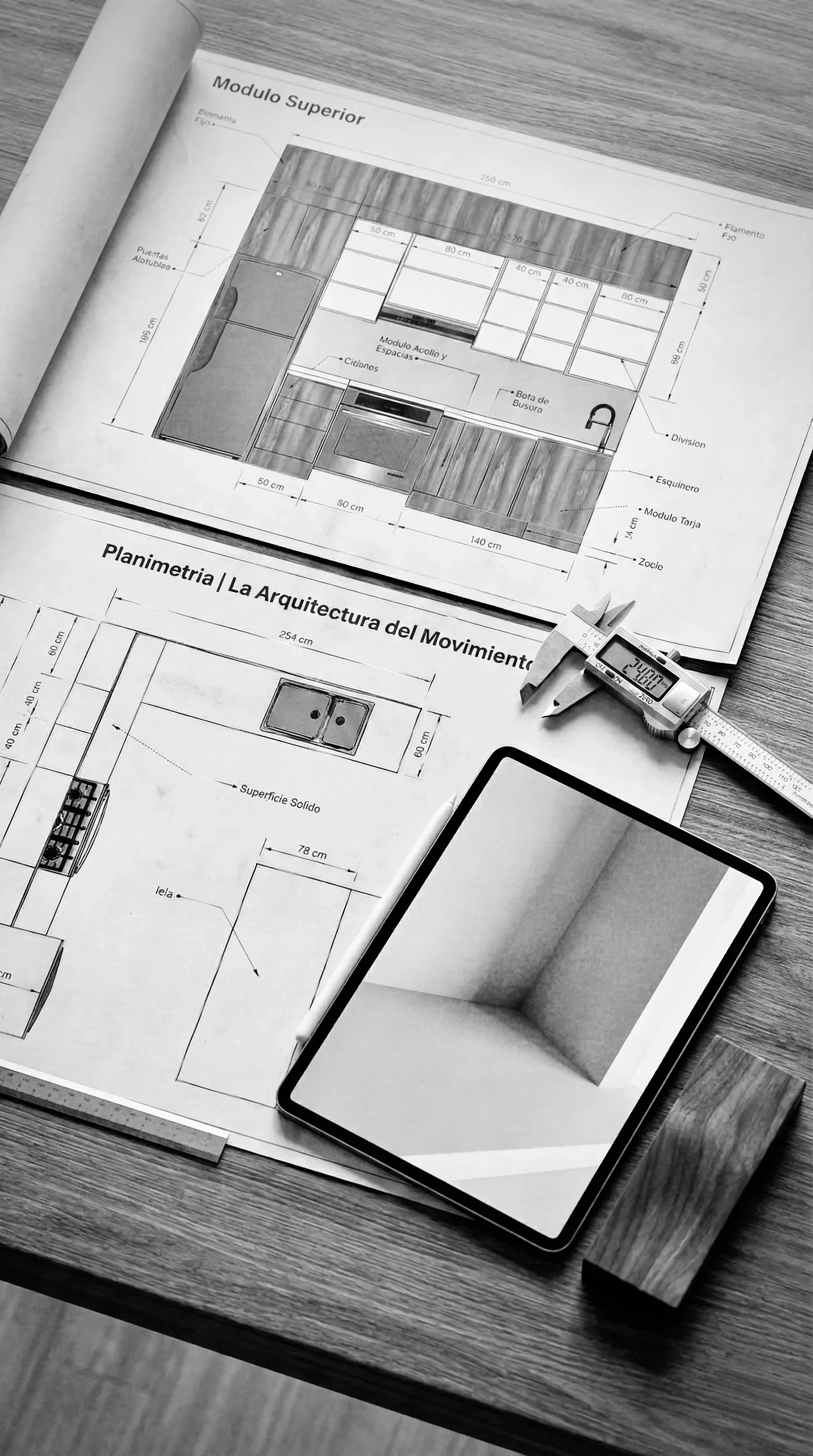 Composición de diseño técnico en Estudio Madera: planos constructivos de planimetría detallada junto a un calibrador digital de alta precisión y una tablet con renderizado 3D de espacios arquitectónicos.