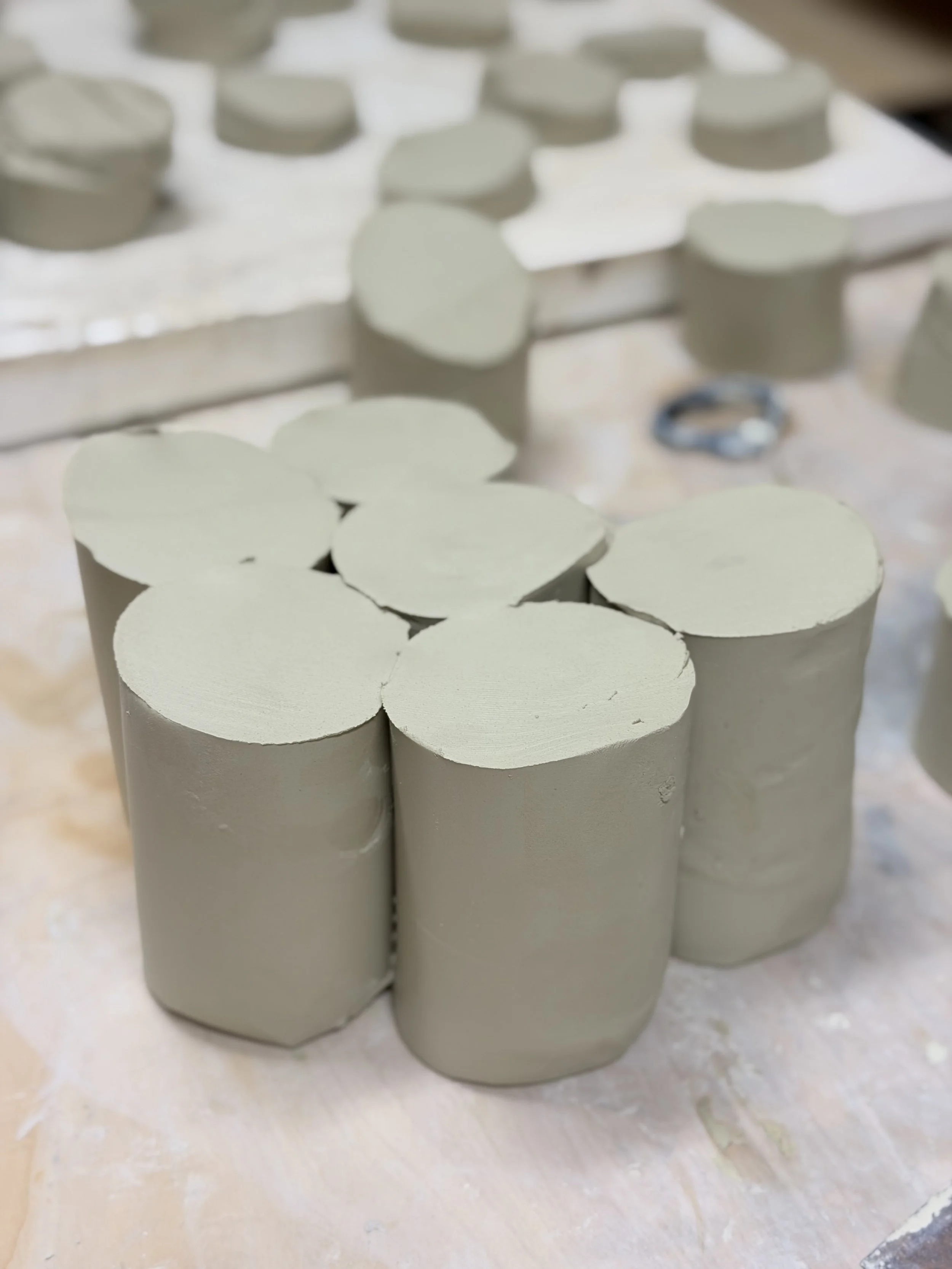 Close-up of white cylindrical objects with flat tops, likely clay or ceramic pieces, arranged on a surface with some scattered material.