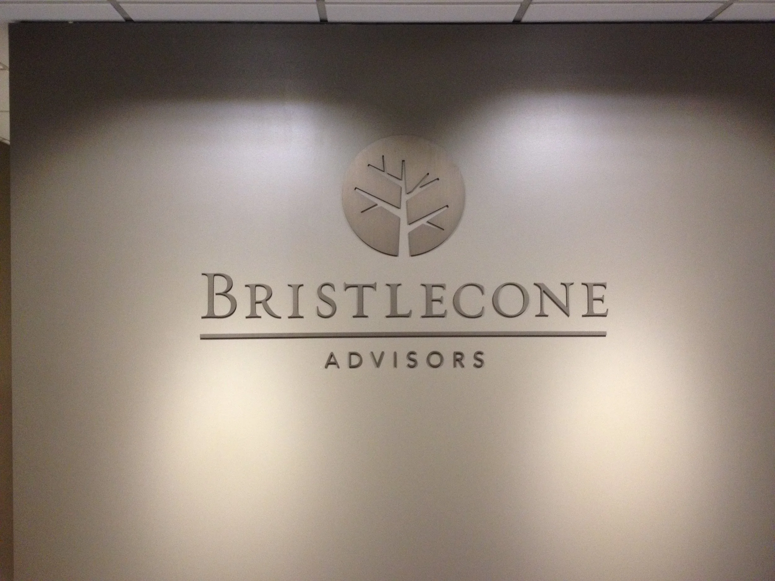Office wall with the Bristlecone Advisors logo, featuring a tree inside a circle and the company name and title.