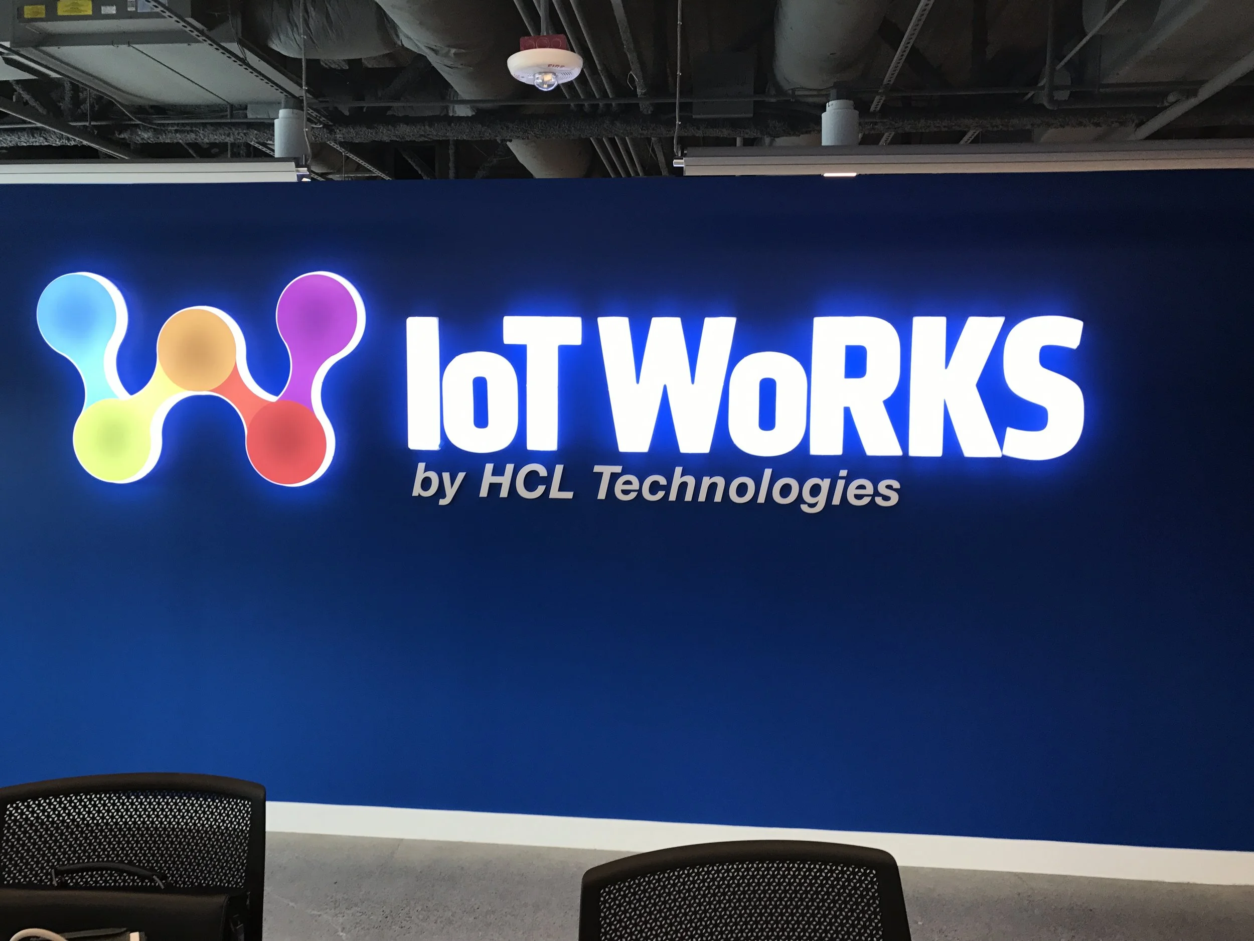 Trade show booth with a blue background displaying the logo and text 'IoT WORKS by HCL Technologies' with a colorful connected nodes graphic.