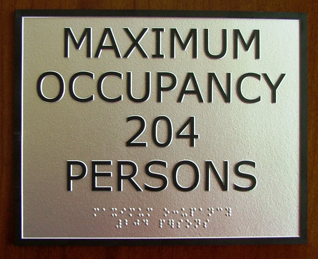 Sign indicating maximum occupancy of 204 persons, with large text and Braille at the bottom.