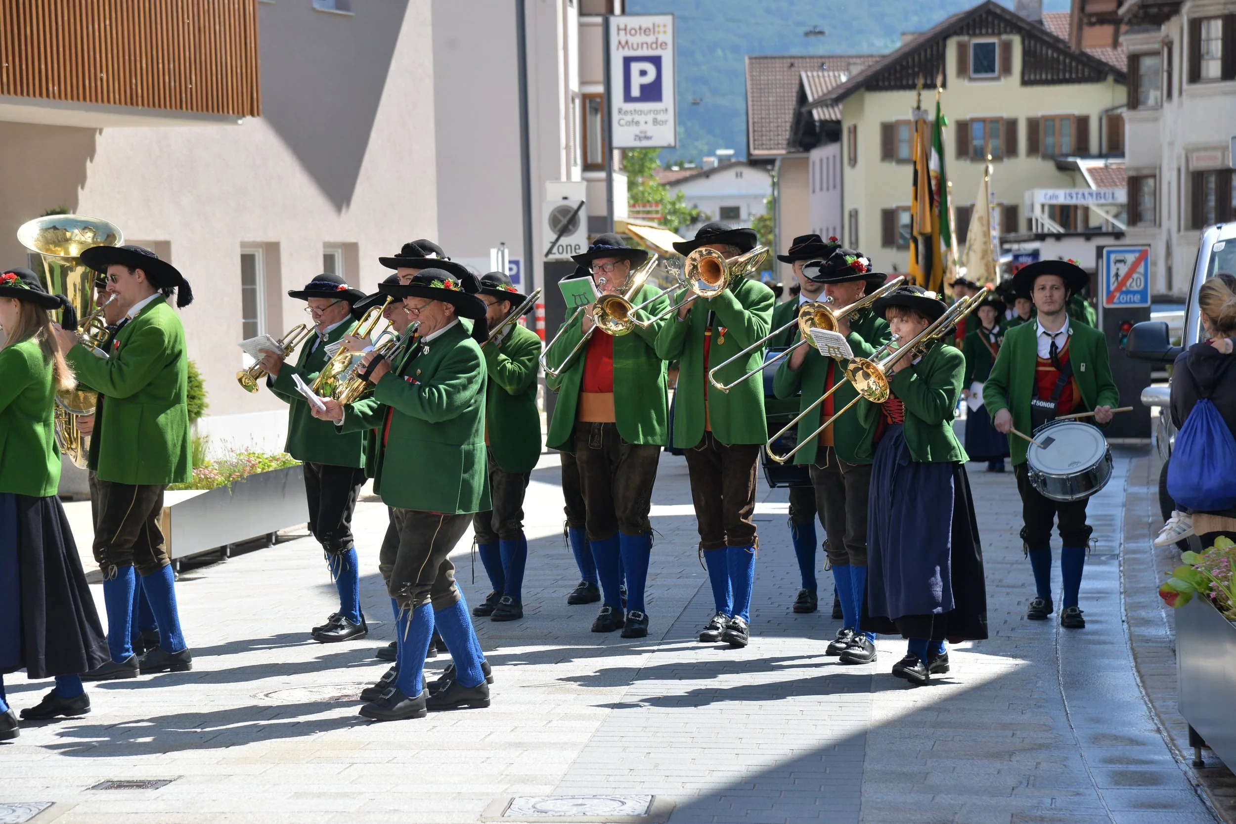Eine Gruppe von Musikern in traditioneller Kleidung, die auf der Straße marschieren und Musik spielen.