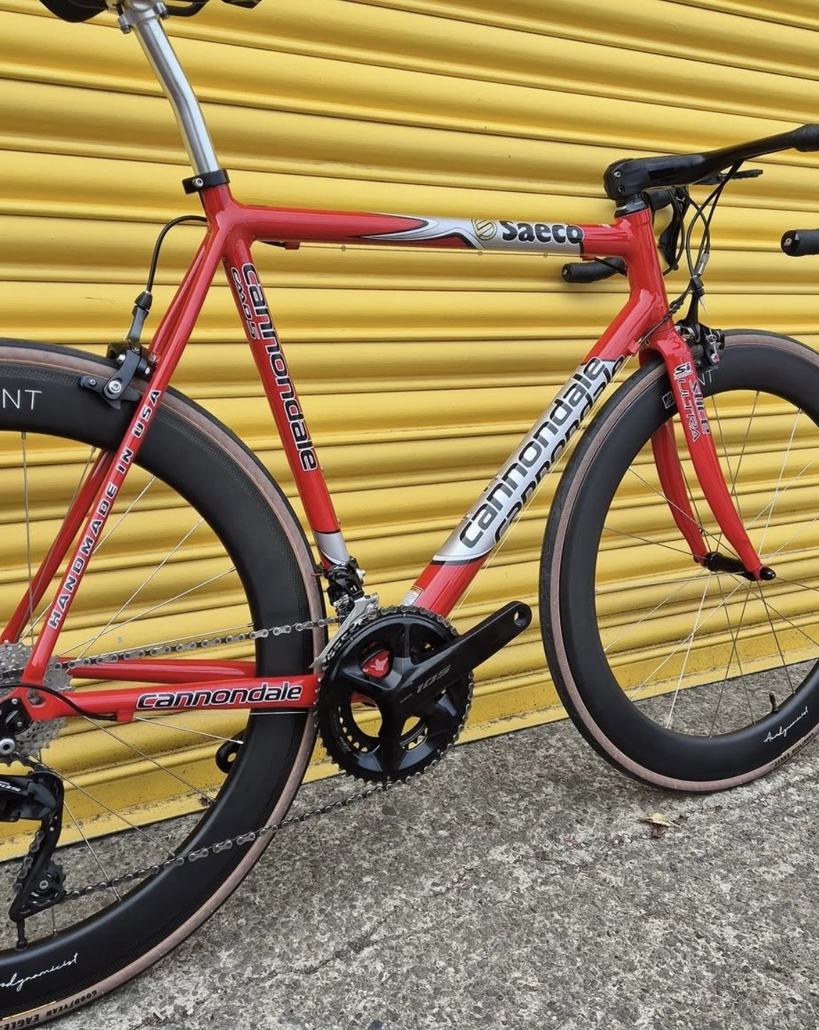 Red Cannondale mountain bike with black tires and yellow background.