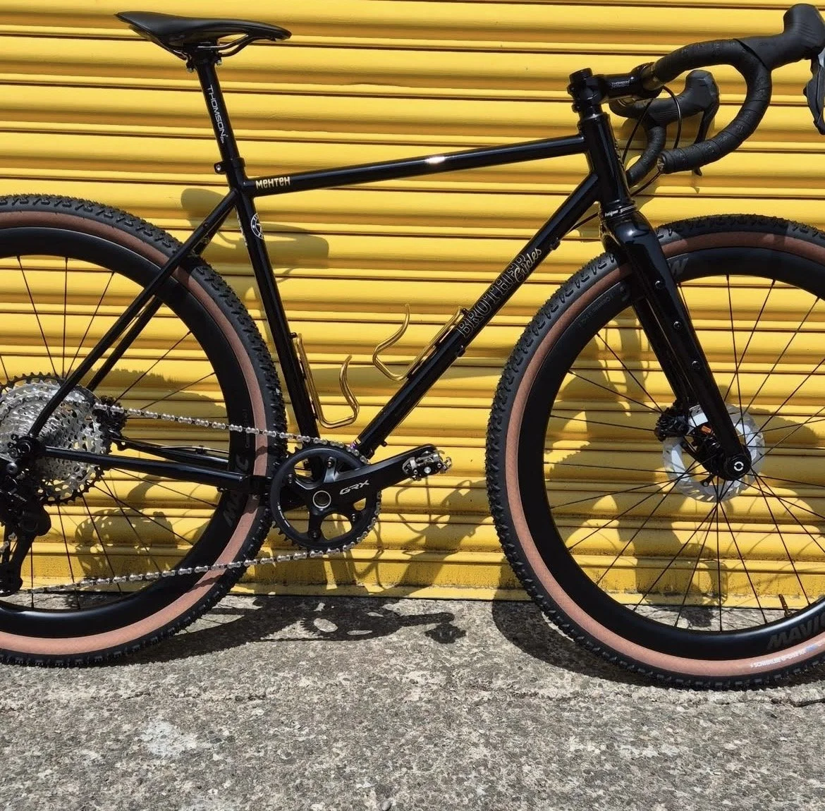 Black mountain bike with pink tires and a yellow roll-up door in the background
