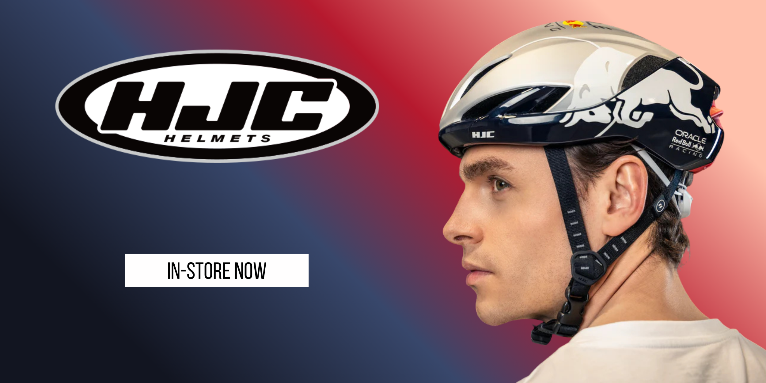Side profile of a man wearing a white and blue bicycle helmet with branding for Red Bull Racing and Oracle, against a background with a gradient from navy blue on the left to light pink on the right, with a black and white HJC Helmets logo and a whit