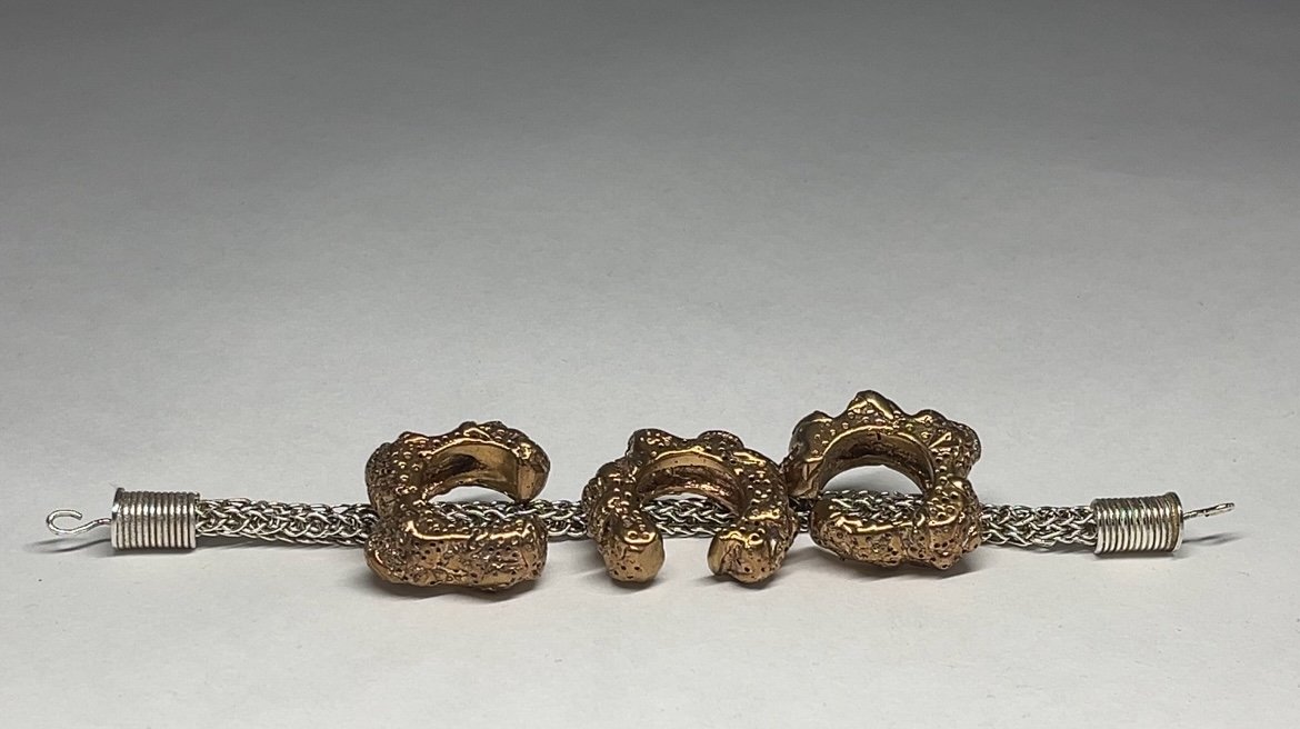 A bracelet with gold-colored, textured dragon-shaped charms and silver links.