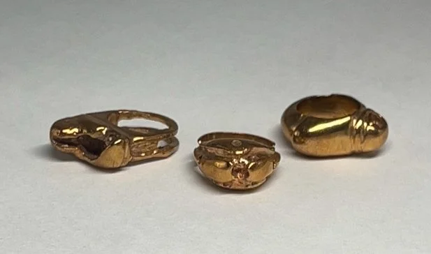 Three gold nuggets of varying sizes on a white surface.