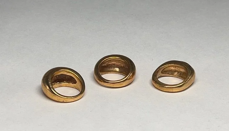 Three gold rings arranged on a white surface.