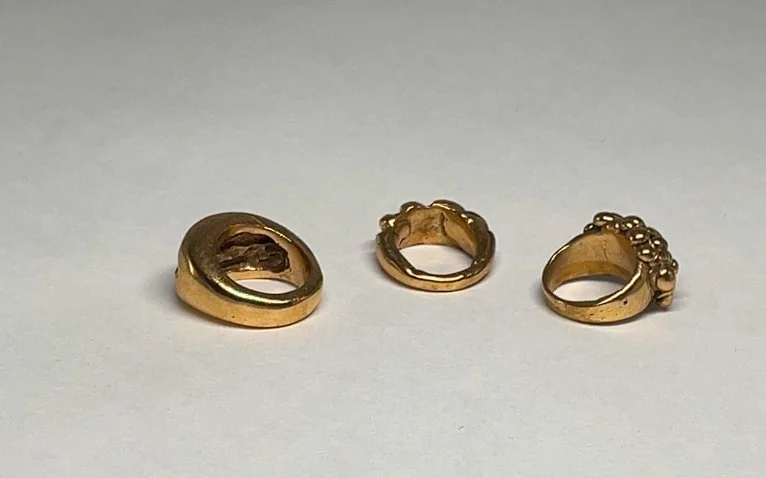 Three gold rings of different styles on a white background.