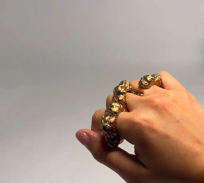 A hand wearing a gold nugget ring and bracelet.