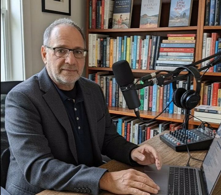 Mitch Gantma AI SEO Expert Sittingat a desk an dtalking into a microphone