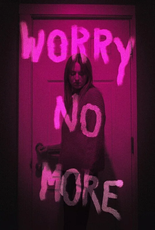 Pink neon sign on a door that says 'Worry No More' with a woman standing in front of it.