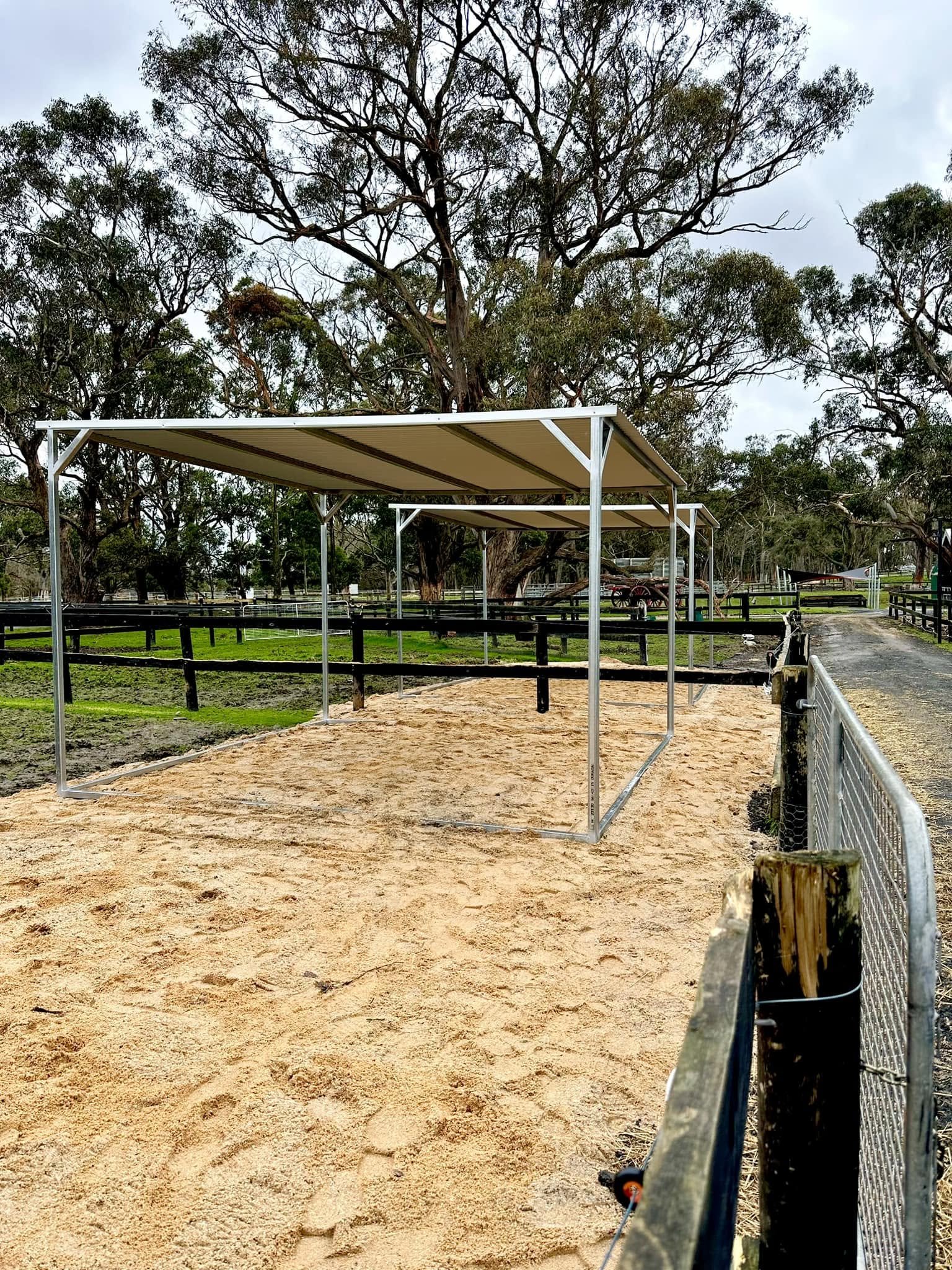 Horse yards with covered shelters and sand footing at an equine veterinary and rehabilitation facility, providing safe outdoor areas for horses receiving veterinary care and recovery.