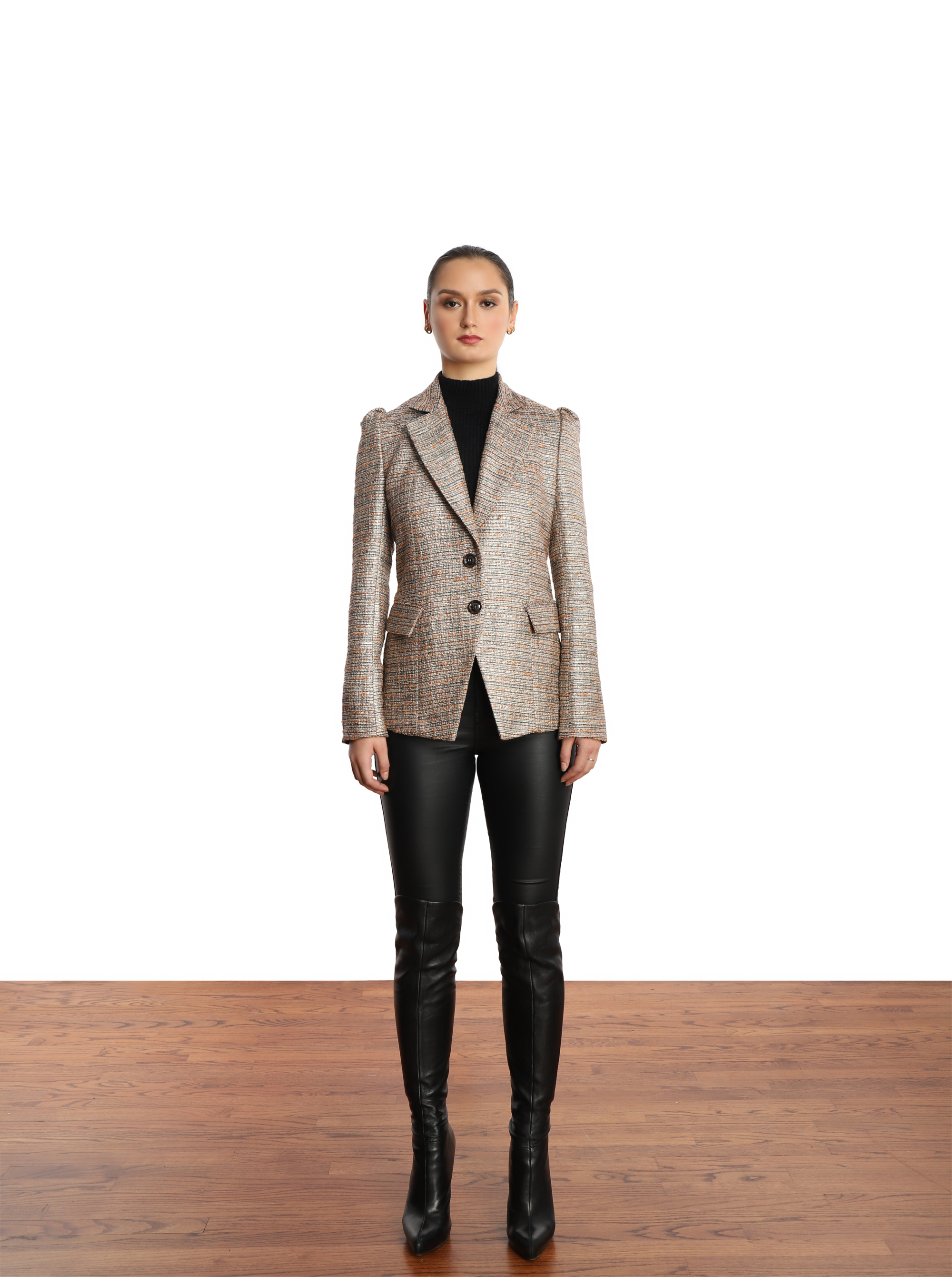Model wearing a silver tweed blazer, black turtleneck with black leather-like leggings and over the knee black leather boots. 