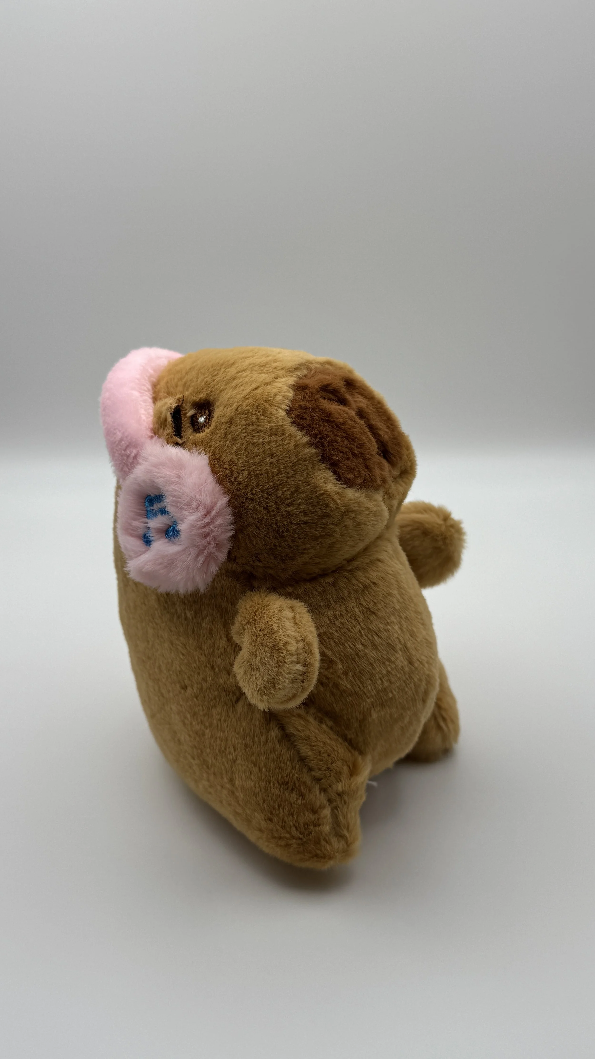 Brown plush toy resembling a hamster with a pink and white fluffy nose and blue eyes.