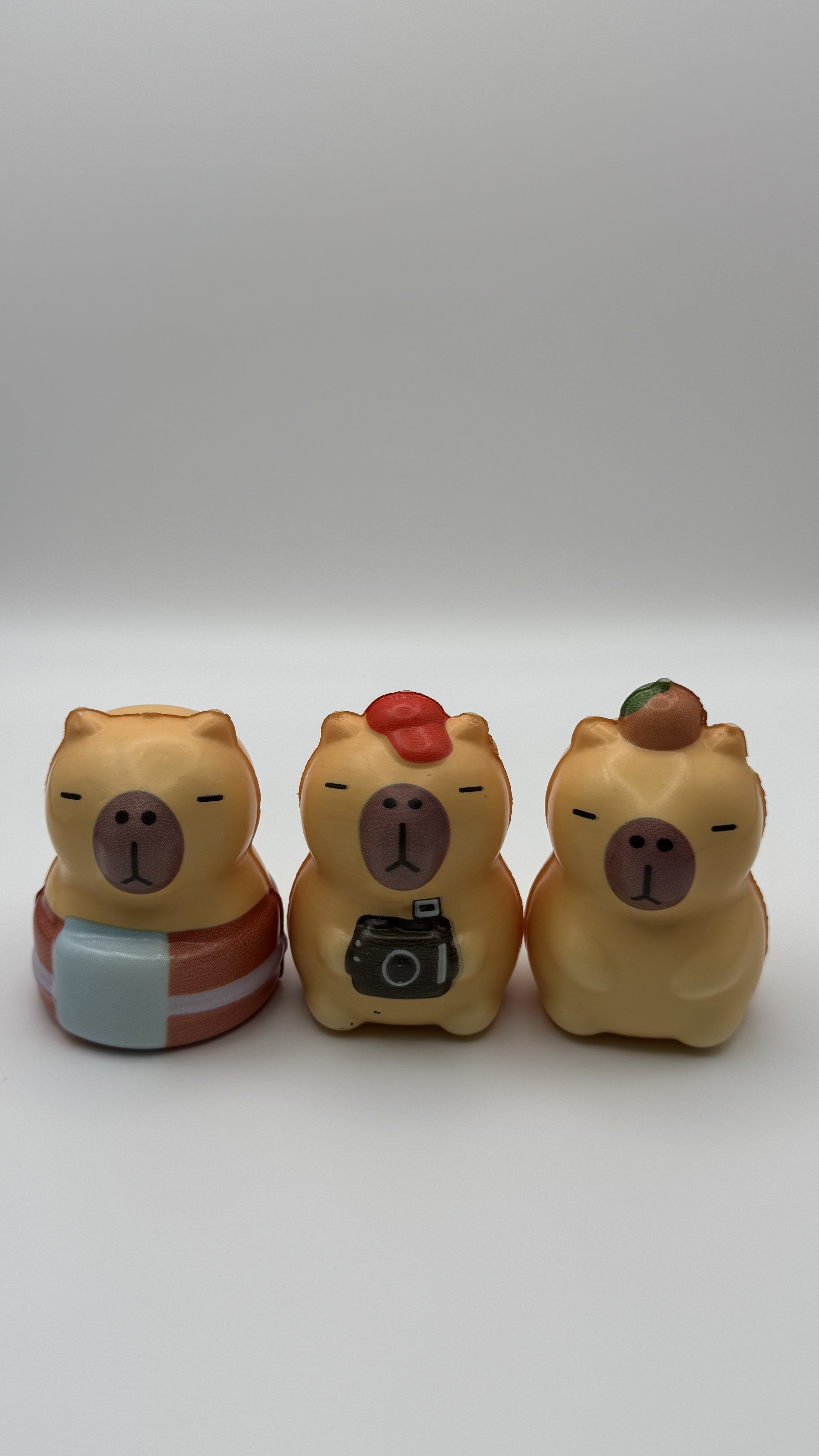 Three small bear-shaped figures with different accessories, sitting on a white surface.