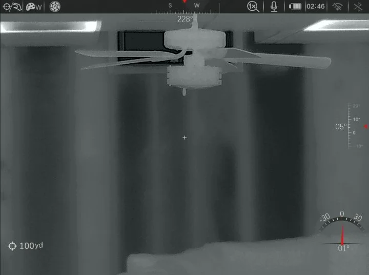 A ceiling fan photographed from below with a thermal or infrared camera showing heat signatures.