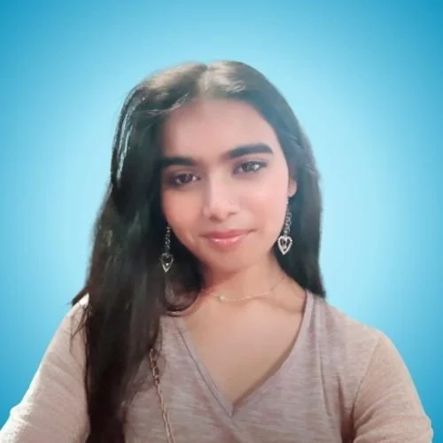 A young woman with long dark hair, wearing heart-shaped earrings and a beige top, smiling gently against a blue background.
