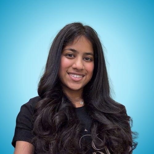 Young woman with long, dark hair smiling against a light blue background